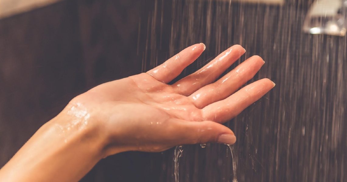 woman's hand under water in shower